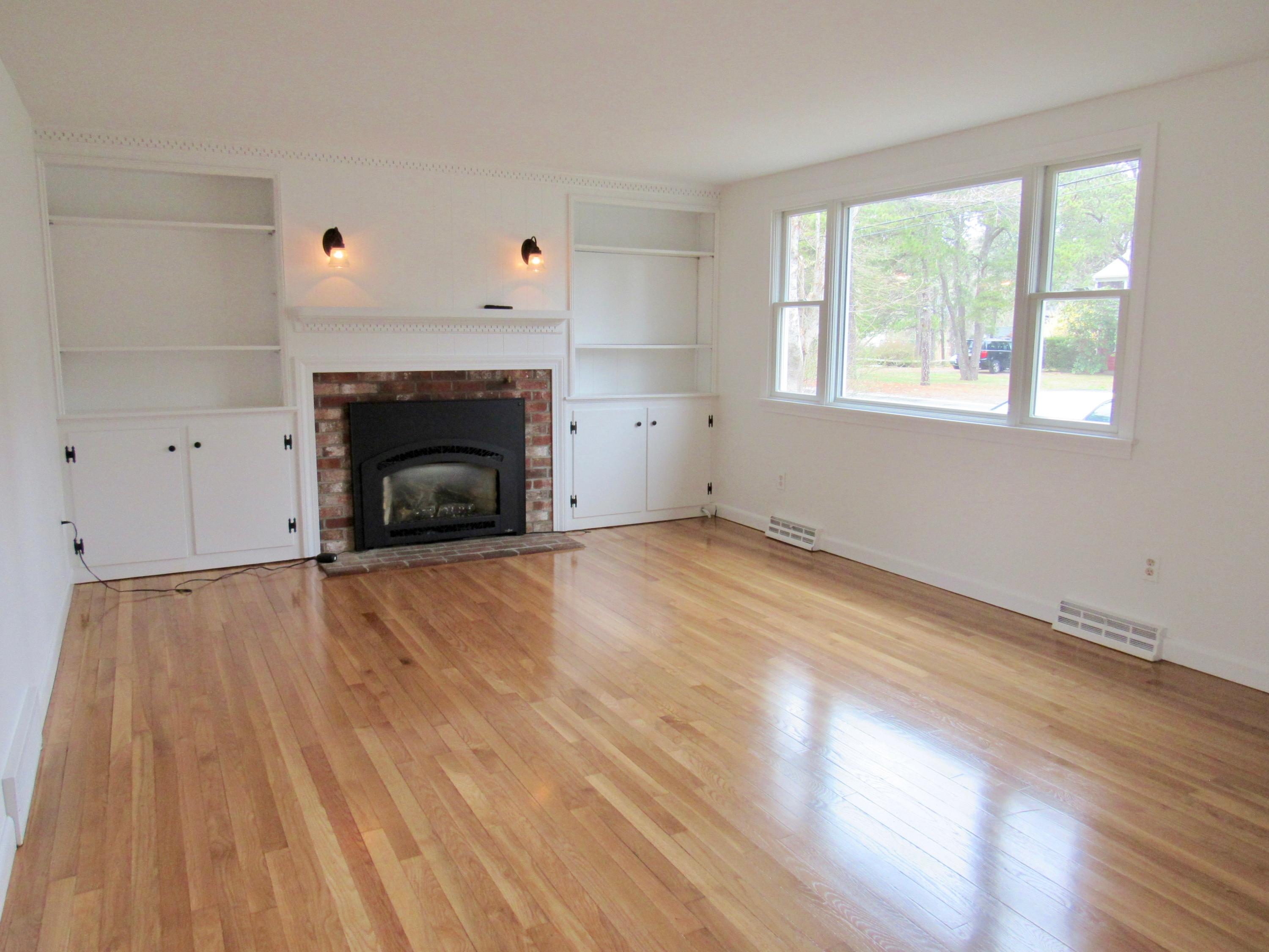 67 Long Road Harwich, MA 02645 - Photo 5 of 30 an empty room with wooden floor fireplace and windows