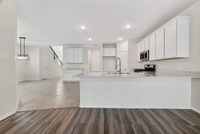 a large white kitchen with wooden floors and white stainless steel appliances