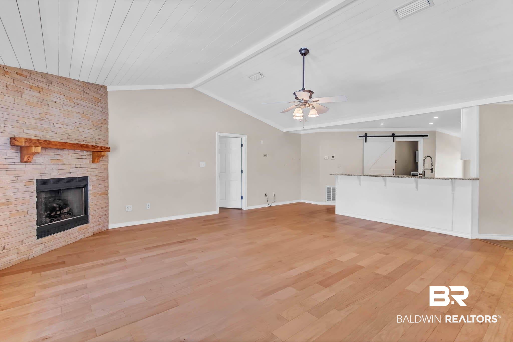 9607 Czar Court Fairhope, AL 36532 - Photo 10 of 42 Unfurnished living room featuring a barn door, light wood finished floors, a stone fireplace, and ceiling fan