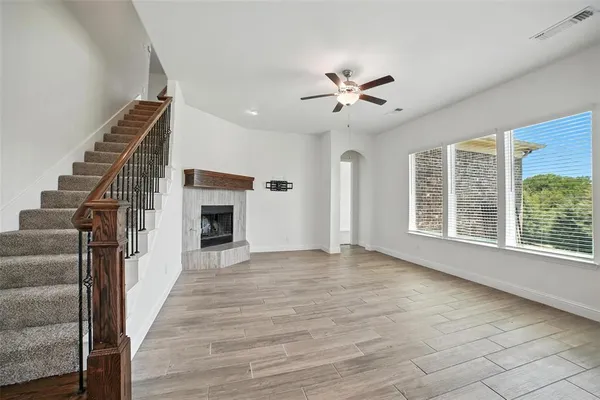 a view of an empty room with wooden floor fireplace and a window