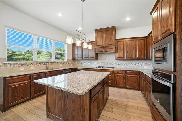 a kitchen with stainless steel appliances granite countertop stove microwave and wooden cabinets