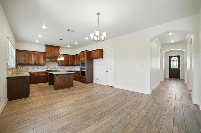 a large kitchen with stainless steel appliances granite countertop a sink dishwasher a stove and a kitchen island with wooden floor
