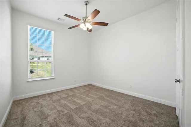 an empty room with windows and fan