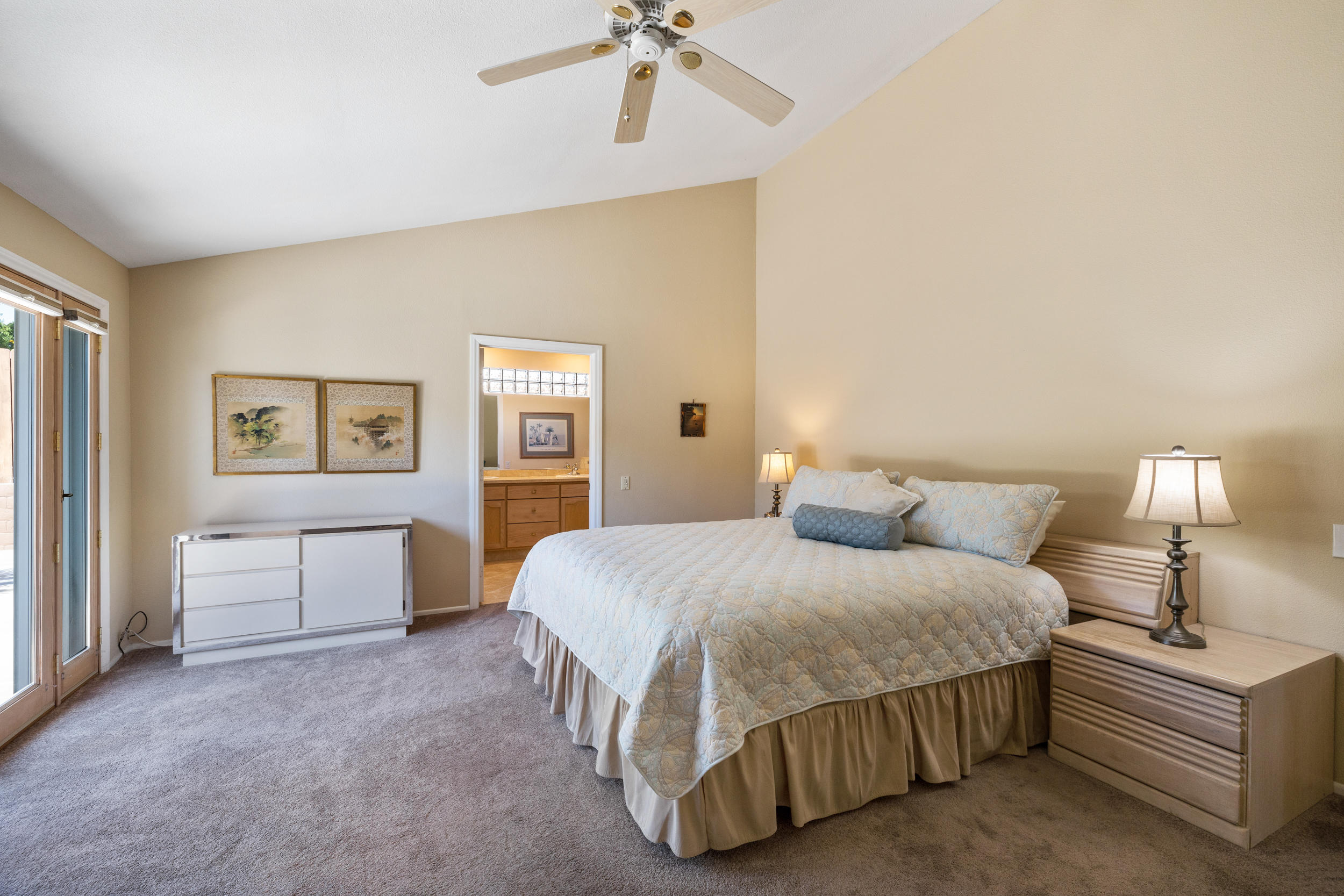 72733 Haystack Road Palm Desert, CA 92260 - Photo 22 of 60 a spacious bedroom with a bed and a chandelier