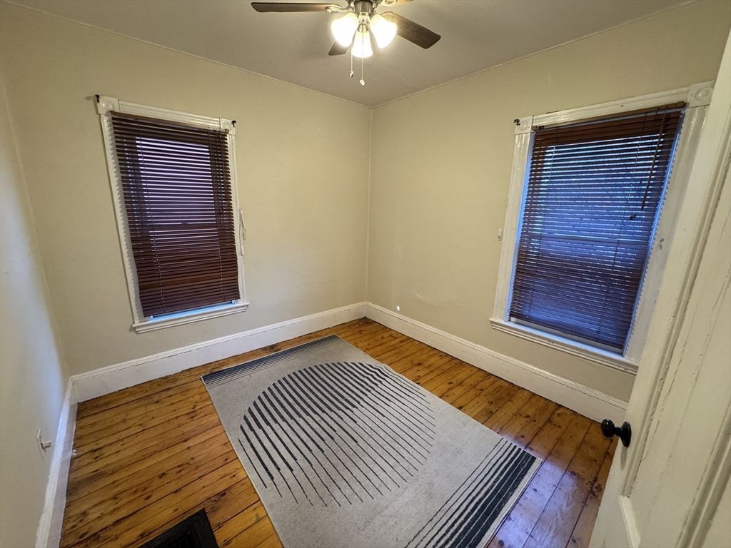 377 Highland Avenue, Unit 1 Somerville, MA 02144 - Photo 12 of 25 a view of an empty room with wooden floor and a window