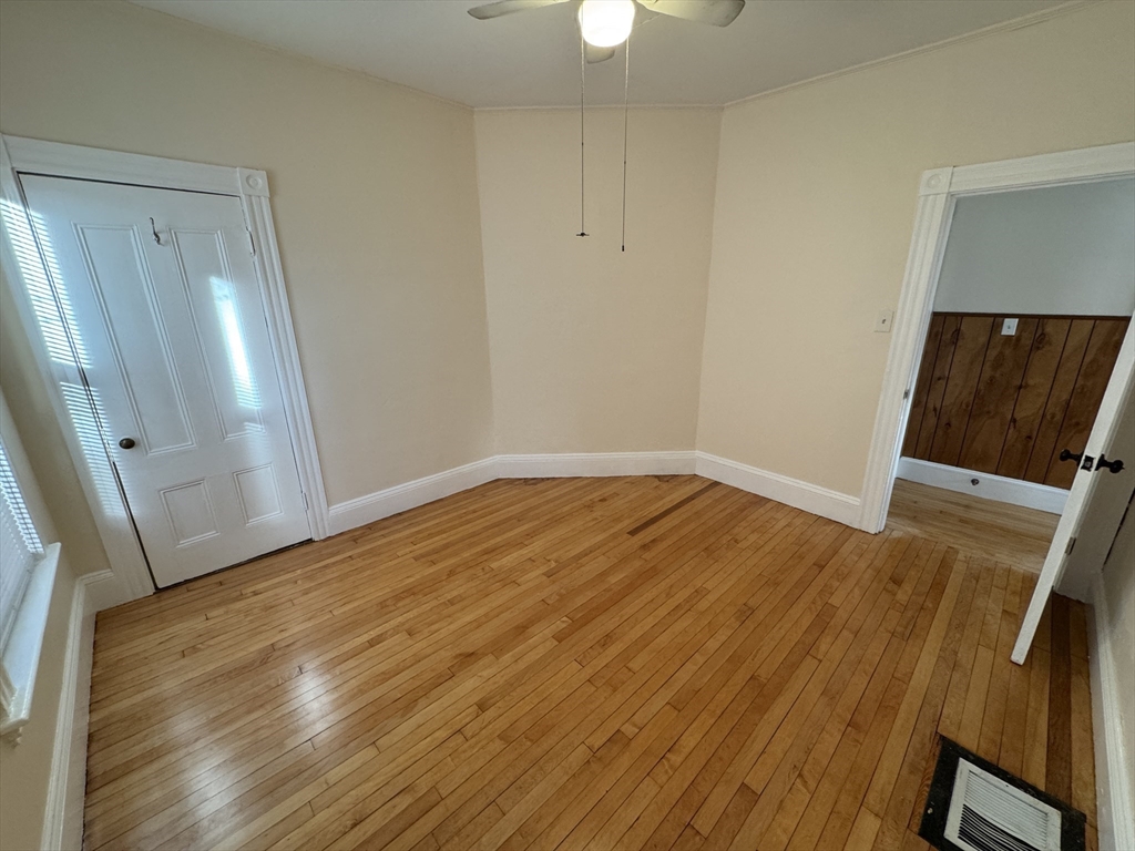 377 Highland Avenue, Unit 1 Somerville, MA 02144 - Photo 15 of 25 a view of an empty room with wooden floor and a window