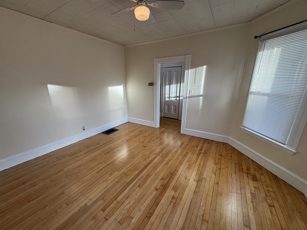 377 Highland Avenue, Unit 1 Somerville, MA 02144 - Photo 2 of 25 a view of an empty room with wooden floor and a window