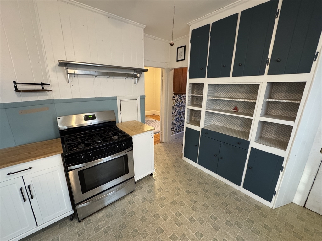 377 Highland Avenue, Unit 1 Somerville, MA 02144 - Photo 4 of 25 a kitchen with white cabinets and black appliances