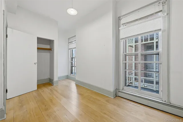 an empty room with wooden floor cabinet and windows
