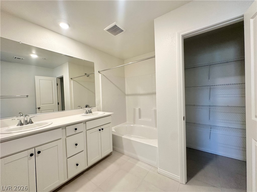 2121 Tricase Street Henderson, NV 89044 - Photo 20 of 31 Bathroom featuring shower / bathtub combination, double vanity, tile patterned flooring, and a walk in closet