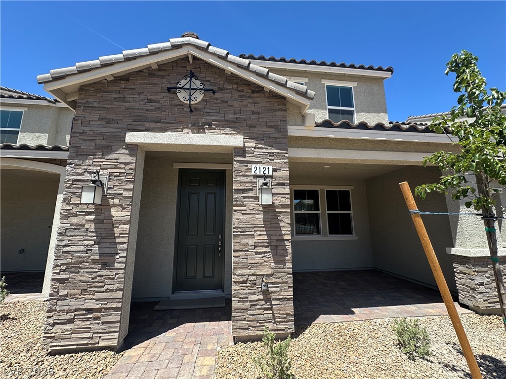 2121 Tricase Street Henderson, NV 89044 - Photo 4 of 31 Property entrance featuring stone siding, stucco siding, and a tiled roof
