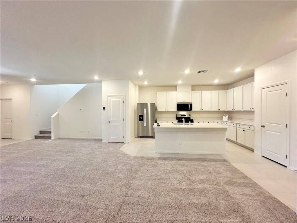 2121 Tricase Street Henderson, NV 89044 - Photo 31 of 31 Kitchen featuring stainless steel appliances, open floor plan, white cabinetry, a kitchen island with sink, and recessed lighting