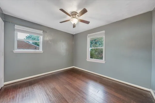 a view of an empty room with wooden floor and a window
