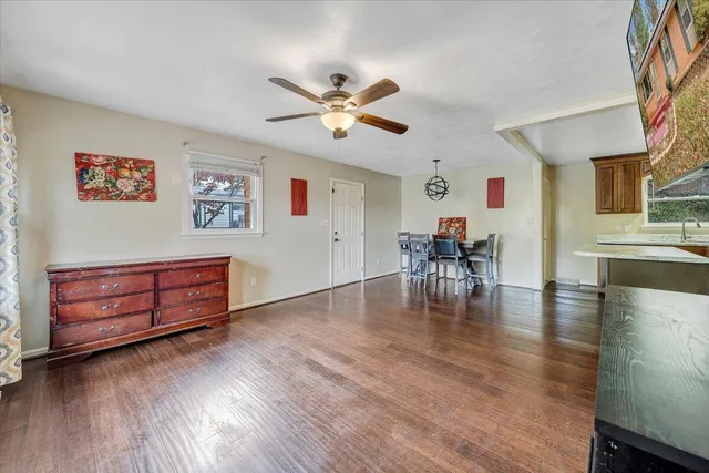 a dining room with wooden floor a chandelier a glass table and windows