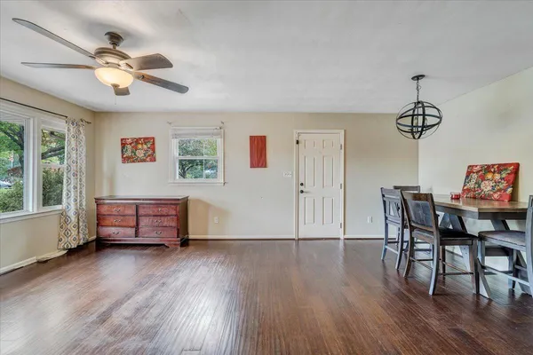 a dining room with wooden floor a chandelier a wooden table and chairs