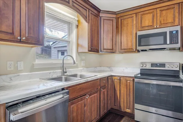 a kitchen with granite countertop a sink stainless steel appliances and cabinets