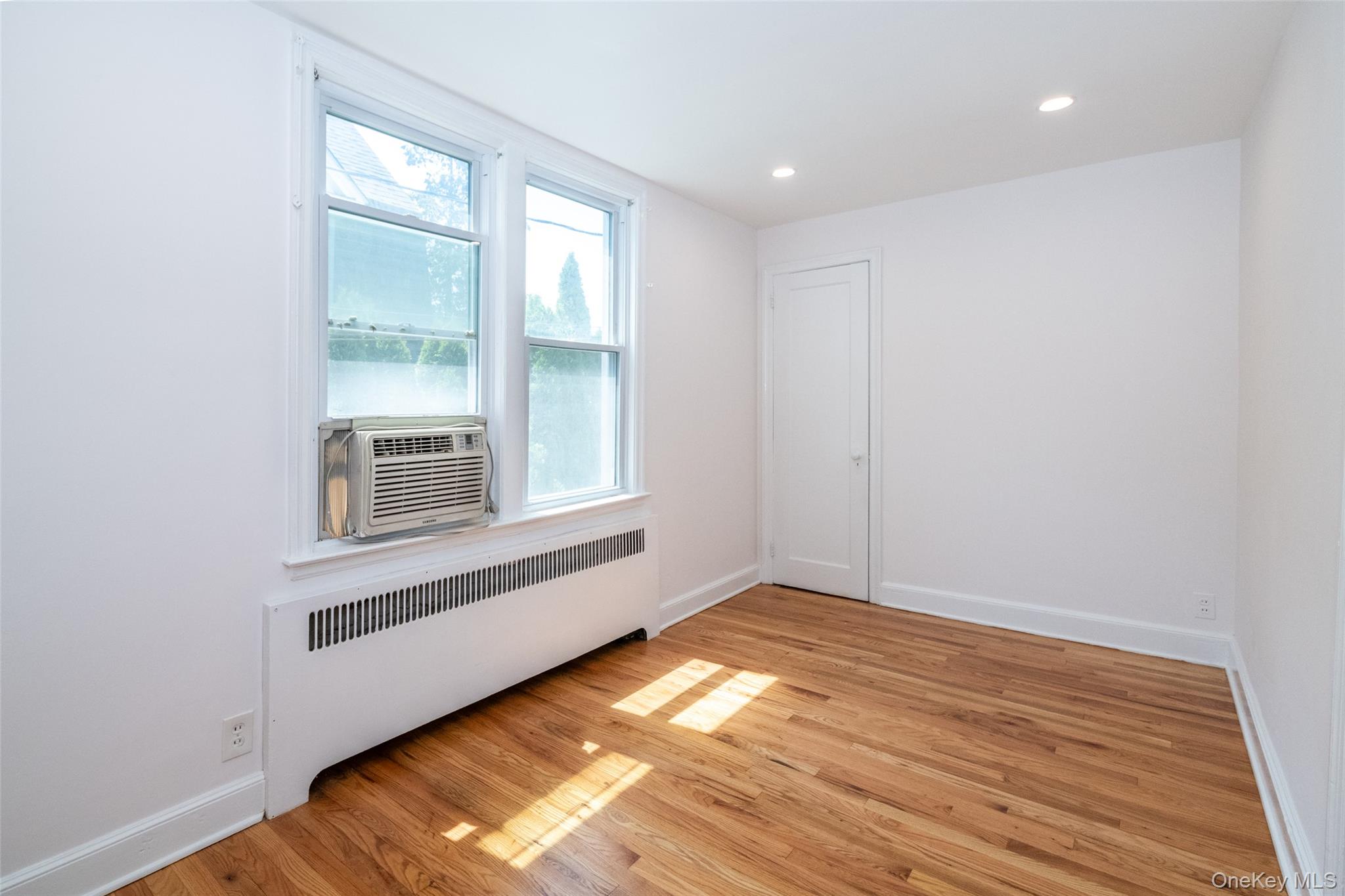 7 Alpha Place, Unit FIRST New Rochelle, NY 10805 - Photo 19 of 25 Spare room with radiator heating unit, light wood-style floors, cooling unit, and recessed lighting