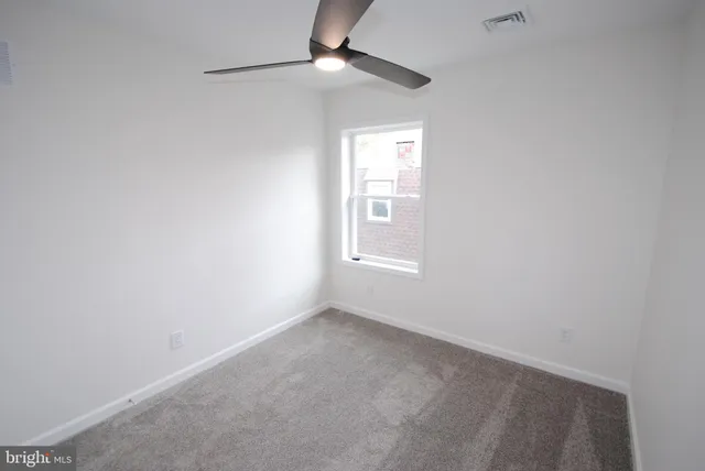 an empty room with a window and ceiling fan