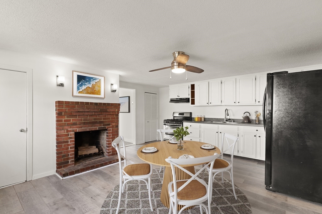 22 Taylor Street, Unit 1 Gloucester, MA 01930 - Photo 7 of 31 a kitchen with stainless steel appliances granite countertop a stove a refrigerator a sink a dining table and chairs with wooden floor