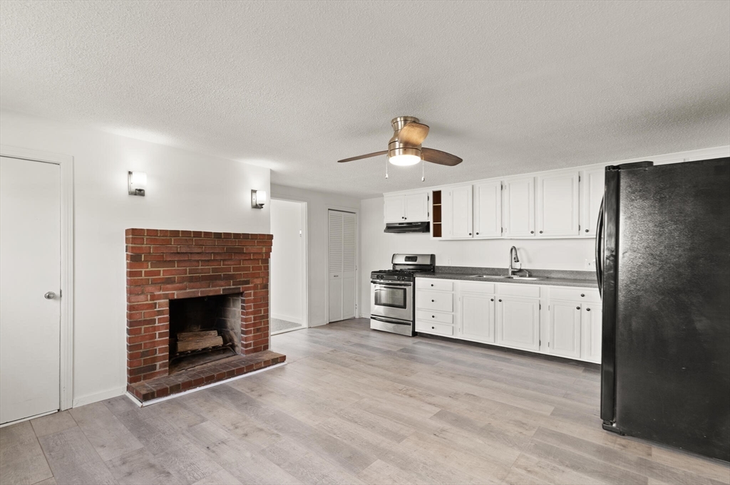 22 Taylor Street, Unit 1 Gloucester, MA 01930 - Photo 8 of 31 a large kitchen with a stove fireplace and wooden floor