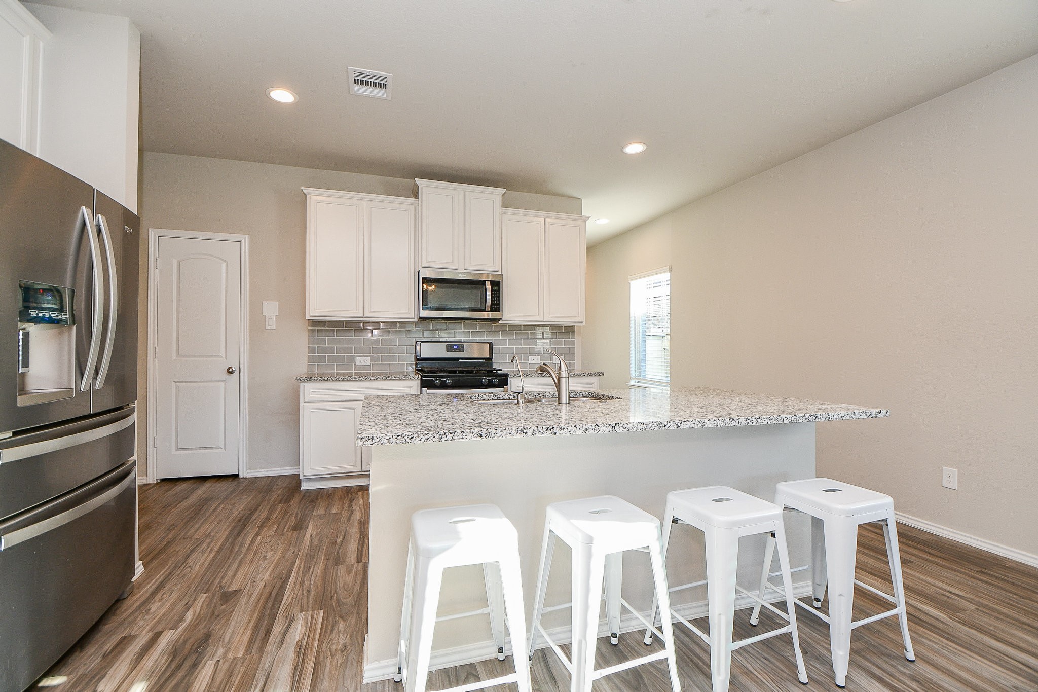 16868 Pink Wintergreen Drive Conroe, TX 77385 - Photo 8 of 32 a kitchen with kitchen island granite countertop a sink refrigerator and microwave