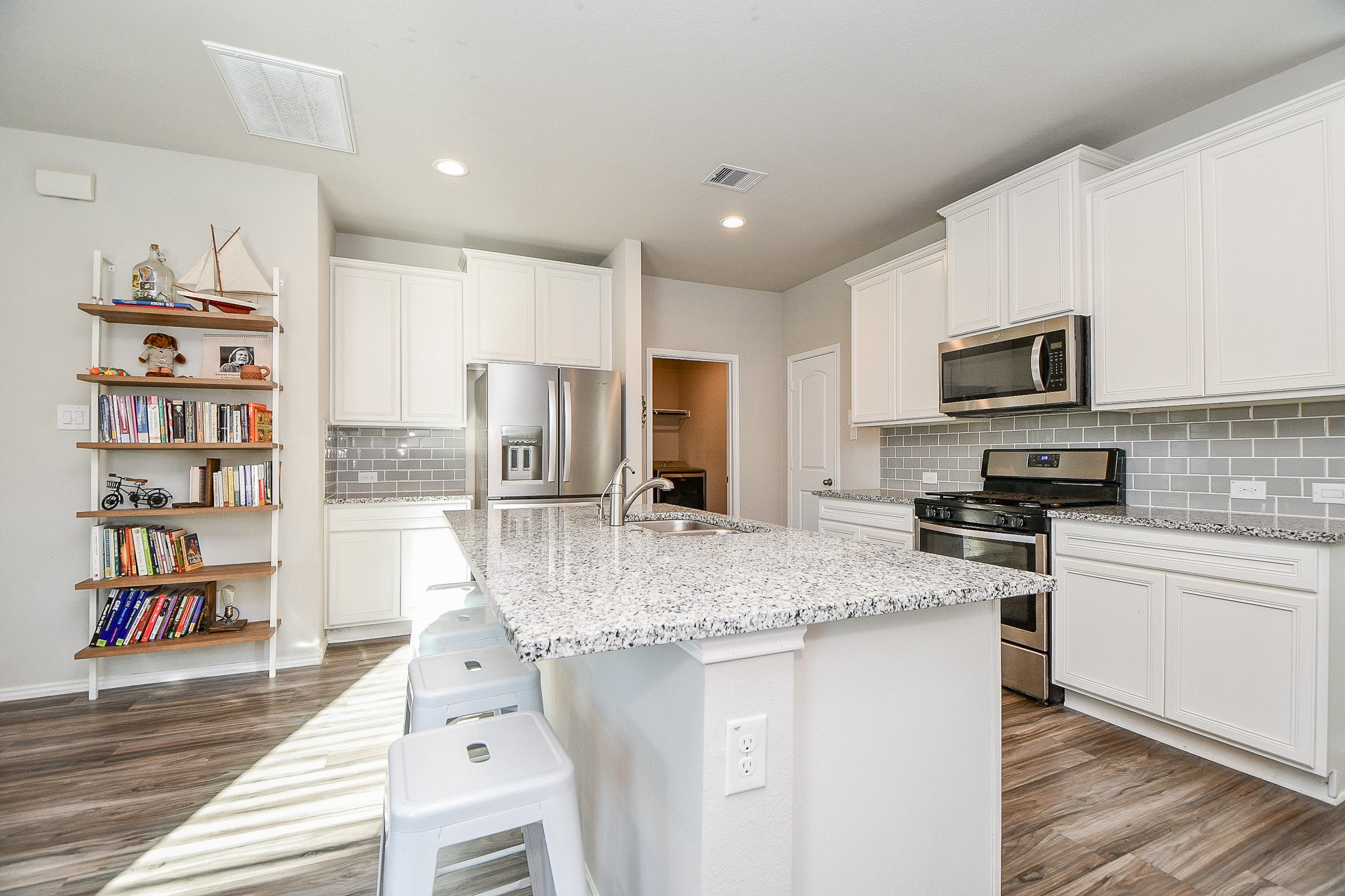 16868 Pink Wintergreen Drive Conroe, TX 77385 - Photo 10 of 32 a kitchen with stainless steel appliances granite countertop a stove top oven a sink dishwasher and a refrigerator with wooden floor