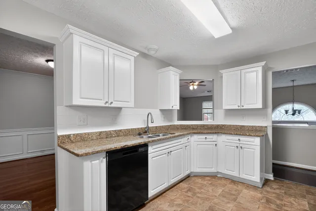 a kitchen with a sink dishwasher a stove and white cabinets