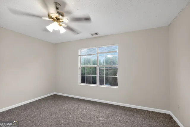 an empty room with a chandelier fan and windows
