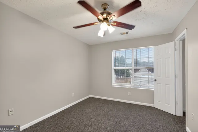 an empty room with a window and a fan