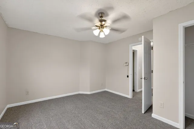 an empty room with a chandelier fan and windows