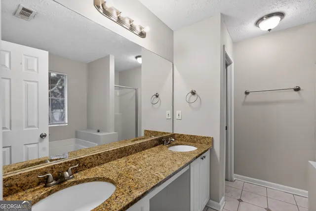 a bathroom with a granite countertop double vanity sink and mirror