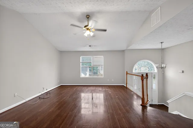 a view of a big room with wooden floor chandelier fan and windows