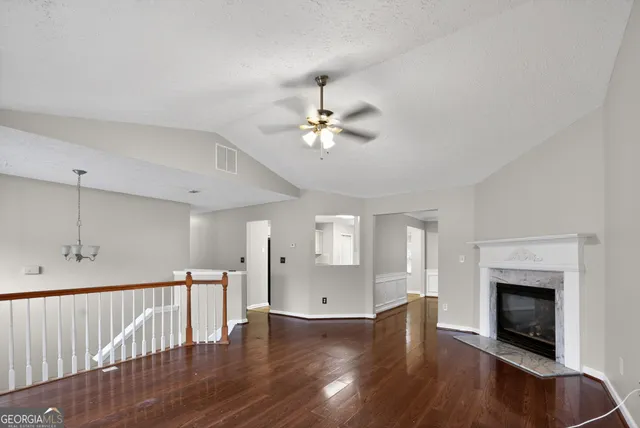 a view of an empty room with wooden floor and a fireplace