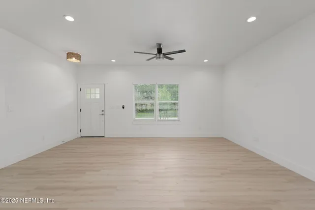 an empty room with a window and a ceiling fan