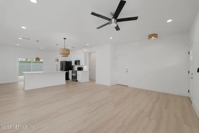 an empty room with wooden floor ceiling fan and windows