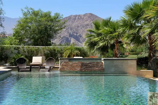 a view of house with swimming pool and outdoor seating