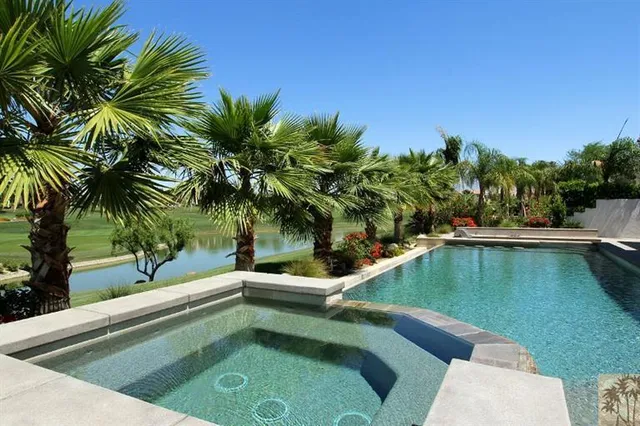 a view of a swimming pool with a chair and palm trees