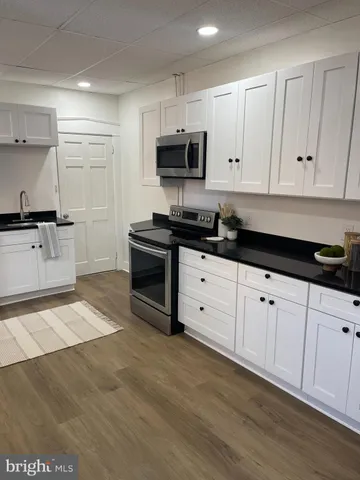 a kitchen with granite countertop a stove a sink and a microwave