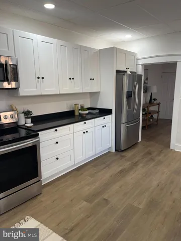 a kitchen with granite countertop a refrigerator stove and white cabinets