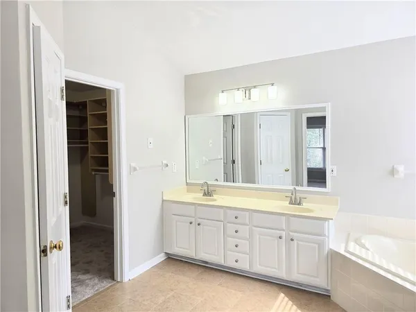 a spacious bathroom with a double vanity sink a large mirror and a bathtub