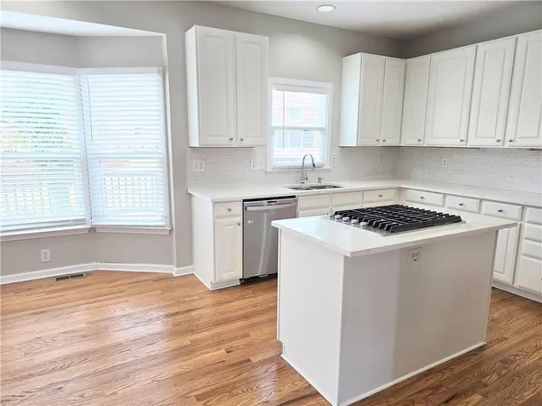 a kitchen with granite countertop white cabinets and white appliances with wooden floor