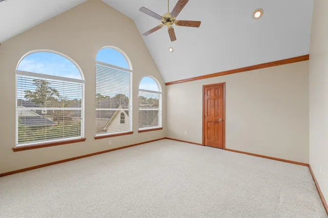 an empty room with windows and fan