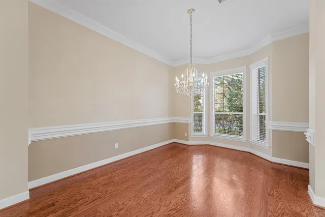 an empty room with windows and chandelier fan