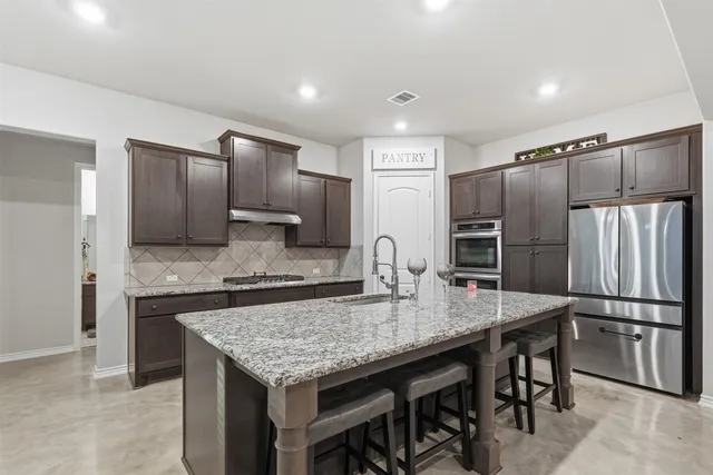 a kitchen with granite countertop stainless steel appliances a refrigerator and microwave