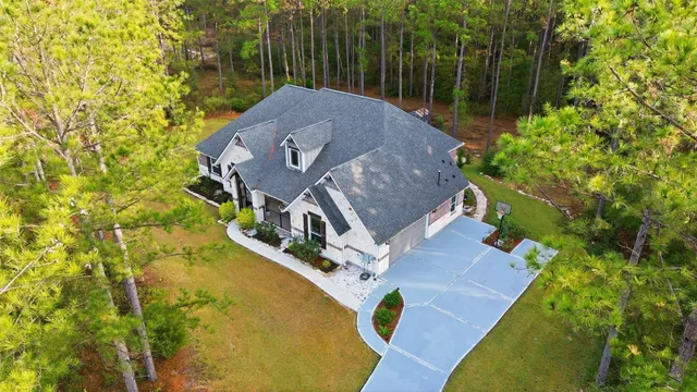 an aerial view of a house with swimming pool and large trees