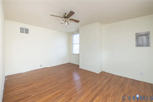 a view of empty room with wooden floor and fan