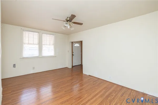a view of an empty room with wooden floor and a window