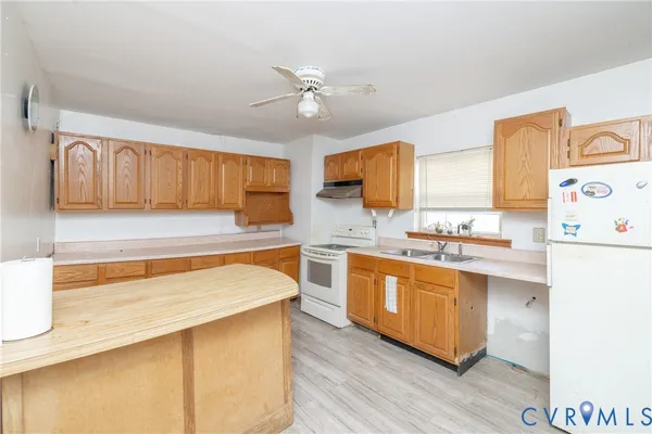 a kitchen with stainless steel appliances granite countertop a sink a stove a refrigerator cabinets and wooden floor