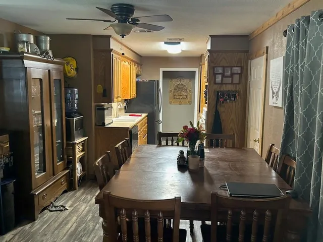 a kitchen with stainless steel appliances granite countertop a refrigerator a stove and a dining table with wooden floor