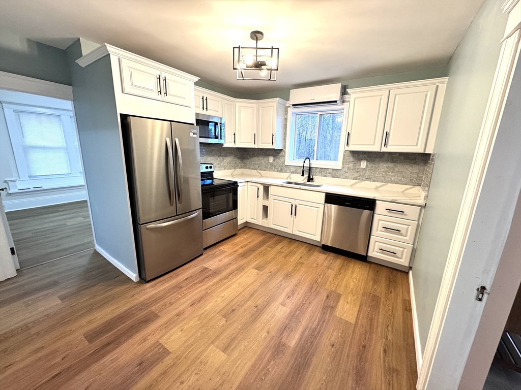9 Idalla Avenue Worcester, MA 01606 - Photo 4 of 16 a kitchen with granite countertop a refrigerator a sink dishwasher and a stove with wooden floor